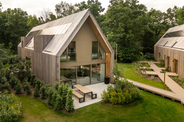 Moderna cabaña de madera con grandes ventanales, terraza y jardín en Lodge at Woodz Lodges, Bélgica.