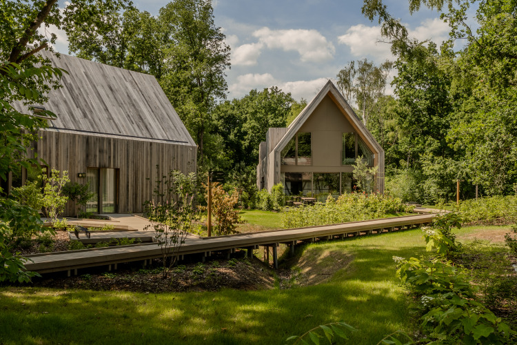Dos cabañas modernas de madera rodeadas de vegetación en Lodge at Woodz Lodges en Bélgica.