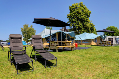 Kampeerterrein met ligstoelen, parasols en tenten op een grasveld in Echternacherbrück, Duitsland.