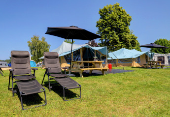 Campground with lounge chairs, umbrellas, and tents on grassy area at Echternacherbrück, Germany.