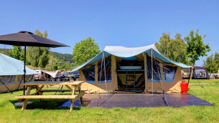 Camping bij Eifel - Echternacherbrück Lodge River met tent, picknickbank en groene natuur.