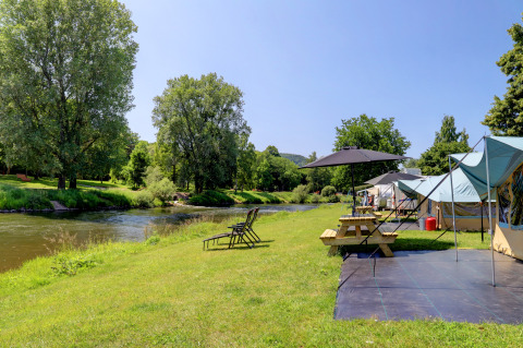 Rivierzicht met kampeertent, picknicktafel en ligstoelen bij Campingpark Echternacherbrück, Duitsland.