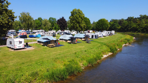 Riviercamping met caravans, tenten en bomen bij DEU/Eifel - Echternacherbrück Lodge River in Duitsland.