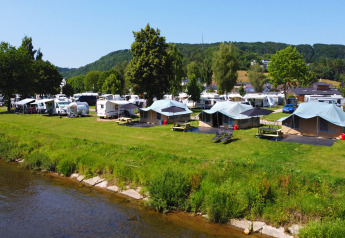 View of tents and caravans by the river at Campingpark Echternacherbrück in scenic Eifel, Germany.