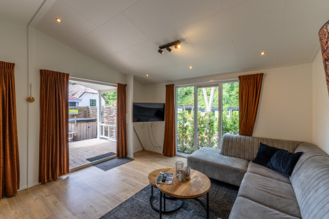 Soggiorno moderno in Family Lodge con divano grigio e vista terrazza a De Thijmse Berg, Paesi Bassi.