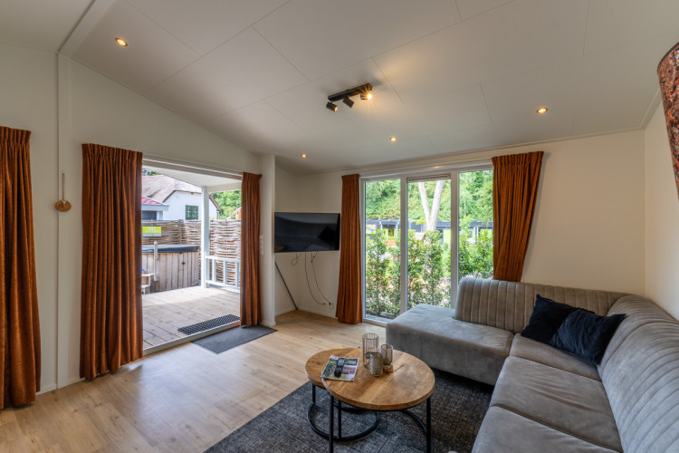 Helles Wohnzimmer in der Family Lodge mit Ecksofa und Ausblick auf Terrasse bei De Thijmse Berg, Niederlande.