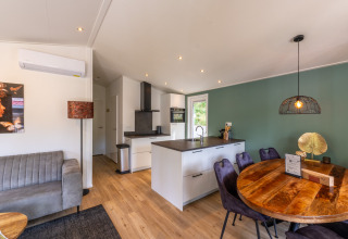 Interno luminoso e moderno della Family Lodge con zona pranzo, cucina e muro verde a De Thijmse Berg, Paesi Bassi.