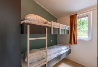 Værelse med køjeseng, træstige, vindue og orange gardin på Family Lodge + hot tub ved De Thijmse Berg.