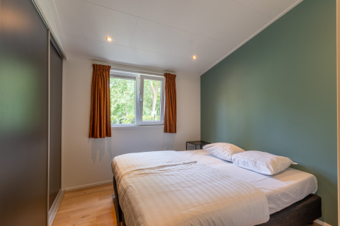 Camera moderna di una family lodge con letto matrimoniale, parete verde e finestra a De Thijmse Berg, Paesi Bassi.