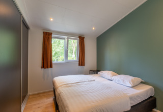 Camera moderna di una family lodge con letto matrimoniale, parete verde e finestra a De Thijmse Berg, Paesi Bassi.