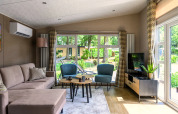 Acogedora sala de estar en lodge con sofá, sillones, mesas, televisor y grandes ventanales al jardín.