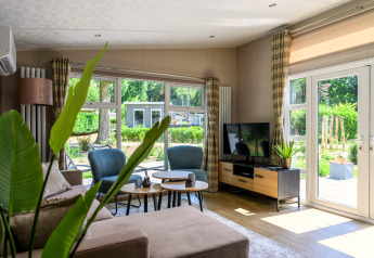 Lichte, moderne woonkamer in Nova 4 personen lodge op Bospark Ede, Nederland, met grote ramen.