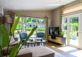 Lichte, moderne woonkamer in Nova 4 personen lodge op Bospark Ede, Nederland, met grote ramen.