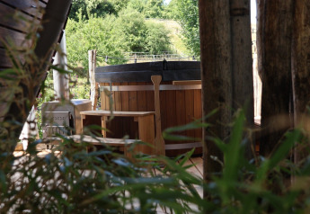 Vasca idromassaggio in legno a Wellnest, Camping Vinkenhof, Paesi Bassi, immersa nel verde e natura.