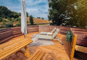 Terrazza in legno soleggiata con lettini e panca presso Wellnest, Camping Vinkenhof, Paesi Bassi.