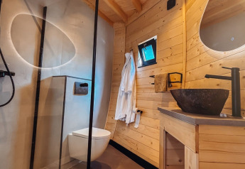Bagno moderno con pareti in legno, doccia, WC e lavandino in pietra al Wellnest, Camping Vinkenhof, Paesi Bassi.