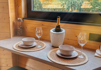 Tavolo per due con vino al Wellnest, Camping Vinkenhof, Paesi Bassi, vicino a una finestra di legno.