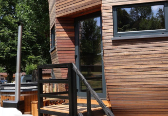 Udendørs træ terrasse og dør ved Wellnest-lodge på Camping Vinkenhof i Holland, omgivet af træer.