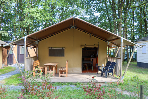 Safaritent Camping Fuussekaul met een overdekt terras, houten banken en stoelen, omringd door groen.