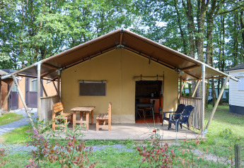 Safari telt Camping Fuussekaul med overdækket terrasse, udendørs træbænk og stole i grønne omgivelser.