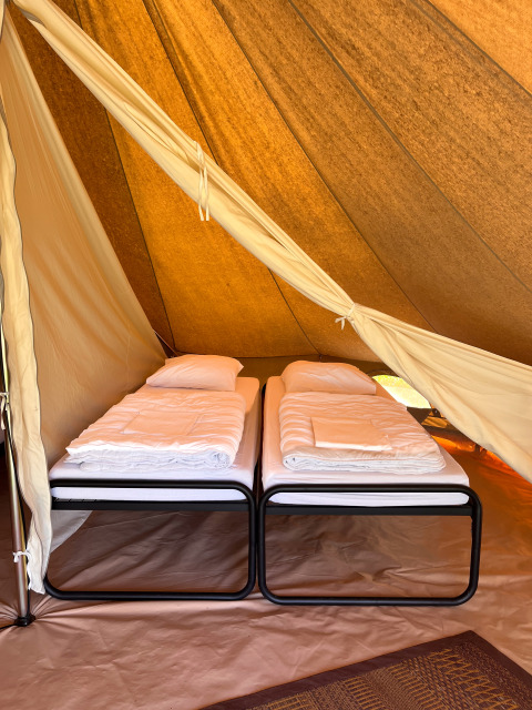 Interior of a tipi tent at Camping Fuussekaul in Luxembourg, showing two single beds ready with white bedding.