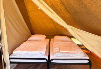 Interior of a tipi tent at Camping Fuussekaul in Luxembourg, showing two single beds ready with white bedding.