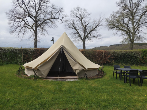 Tipi au Camping Liefrange avec l'entrée ouverte, pelouse, table, chaises et arbres en arrière-plan.