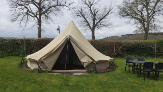 Tipitent op Camping Liefrange met open ingang, grasveld, tafel en stoelen en bomen op de achtergrond.