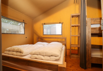 Soveværelse i en safaritelte på Camping Fuussekaul i Luxembourg med dobbeltseng og køjesenge.