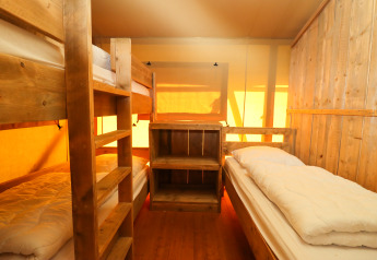 Interno di una tenda safari con letti a castello e letto singolo in legno al Camping Fuussekaul, Lussemburgo.