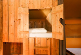 Wooden cabin bed with open doors inside a safari tent at Camping Fuussekaul in Luxembourg.