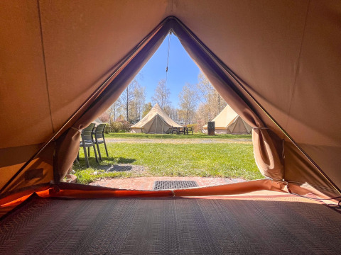 Uitzicht vanuit een tipi-tent op Camping Fuussekaul in Luxemburg, kijkend naar grasveld en andere tenten.