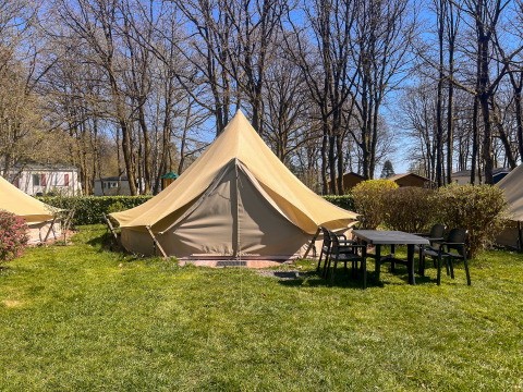 Tenda tipi al Camping Fuussekaul con tavolo e sedie davanti, circondata da alberi e prato verde.