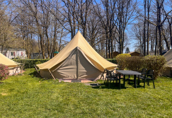 Tenda tipi al Camping Fuussekaul con tavolo e sedie davanti, circondata da alberi e prato verde.