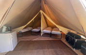 Binnenkant van een tipi tent met vier bedden, koelkast en opbergruimte op Camping Fuussekaul in Luxemburg.