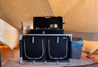 Angolo cottura con fornello a gas, pentola e pattumiera in una tenda tipi al Camping Fuussekaul, Lussemburgo.