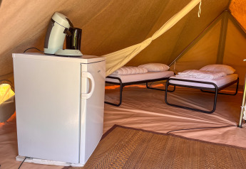 Binnenzijde van een tipi-tent op Camping Fuussekaul in Luxemburg met twee bedden, koelkast en koffietoestel.
