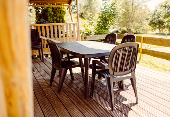 Buiteneethoek met zwarte plastic tafel en stoelen op het terras van een safaritent bij Camping Liefrange, Luxemburg.