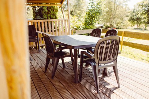 Coin repas extérieur avec table et chaises en plastique noir sur la terrasse d'une tente safari à Camping Liefrange, Luxembourg.