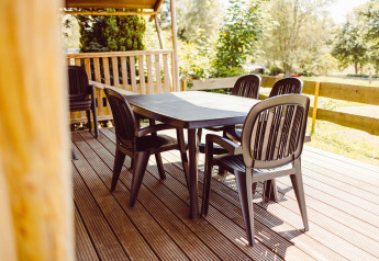 Outdoor dining area with black plastic table and chairs on the terrace of a safari tent at Camping Liefrange, Luxembourg.