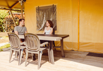 Twee mensen zitten aan een tafel buiten een safaritent op Camping Liefrange in Luxemburg.