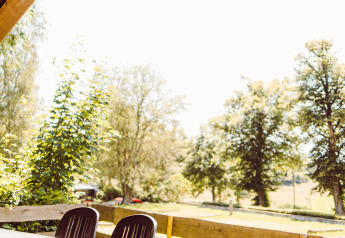 Uitzicht vanaf een safaritent-terras met zwarte tafel en stoelen bij Camping Liefrange in Luxemburg, omgeven door natuur.