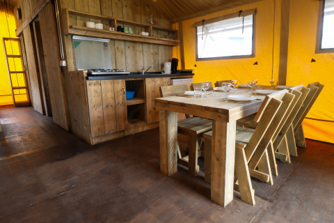 Cucina rustica e zona pranzo in tenda safari al Camping Liefrange in Lussemburgo con arredamento in legno.