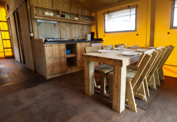 Rustic kitchen and dining area in a safari tent at Camping Liefrange in Luxembourg with wooden furniture.