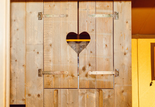 Porta di legno con decoro a cuore in una tenda safari al Camping Liefrange in Lussemburgo.