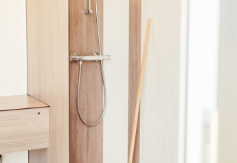 Shower with wood panels and handheld showerhead in a safari tent at Camping Liefrange in Luxembourg.