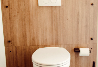 Modern hangtoilet met houten wand, toiletrol en borstel in een safaritent op Camping Liefrange Luxemburg.