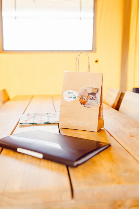 Paper bag, notebook, and cloth on wooden table inside safari tent Camping Liefrange in Luxembourg, sunny day.
