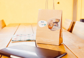 Paper bag, notebook, and cloth on wooden table inside safari tent Camping Liefrange in Luxembourg, sunny day.