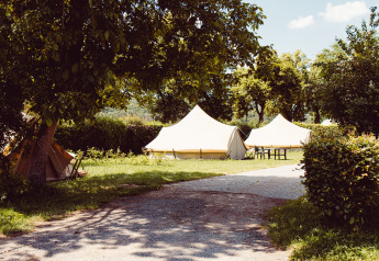 Campingplatz mit Tipi-Zelten unter grünen Bäumen bei Camping Liefrange in Luxemburg an einem Sommertag.